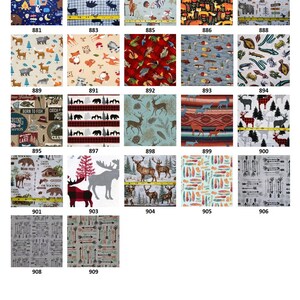 Puede incluir: Una colecci&oacute;n de veintid&oacute;s muestras de tela con varios patrones de aire libre y vida silvestre, incluyendo osos, ciervos, zorros, peces, flechas y motivos de camping, cada una con un n&uacute;mero de identificaci&oacute;n y algunas mostrando una regla amarilla.