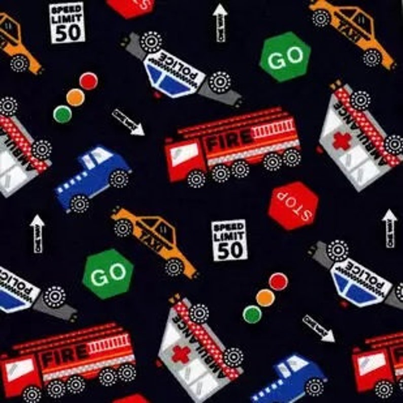 May include: A black fabric featuring a repeating pattern of emergency vehicles including red fire trucks, white ambulances, blue trucks, and yellow taxis. The design includes traffic signs reading Speed Limit 50, Stop, Go, and One Way arrows.