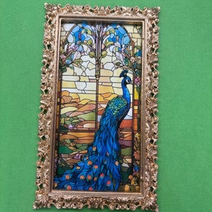 May include: A framed print of a stained glass window featuring a peacock with blue and green feathers. The window is set against a background of a landscape with trees and flowers.