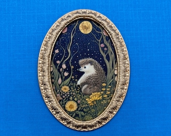May include: A gold oval frame with a detailed design surrounds a painting of a hedgehog sitting in a field of flowers under a full moon. The hedgehog is brown and white with a pink nose. The flowers are yellow, pink, and white.