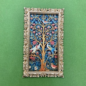 May include: A gold framed picture with a tapestry depicting a stylized tree with birds and flowers. The tree has a dark blue background with pink and blue flowers. The birds are white, blue, and red.