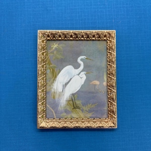 May include: A framed print of two white egrets standing in a marsh setting. The print is in a gold frame with a decorative border.