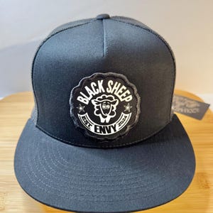 May include: Black trucker hat with a black and white patch that says "Black Sheep Est. 2024 Envy" with a cartoon sheep in the center.