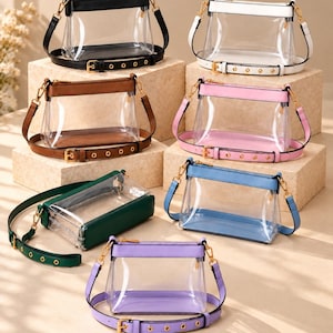 May include: A collection of seven clear crossbody bags with solid-colored trim and adjustable straps. Each bag features a transparent main compartment, a zippered top closure, and gold-tone metal hardware. The bags are available in black, white, brown, pink, dark green, light blue, and lavender.