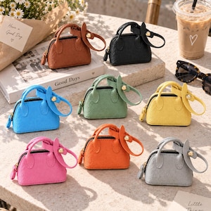 May include: A collection of eight miniature handbags in various colors including brown, black, blue, green, yellow, pink, orange, and gray. Each small bag features a top handle, a zipper closure, and a decorative circular charm attached to the side.