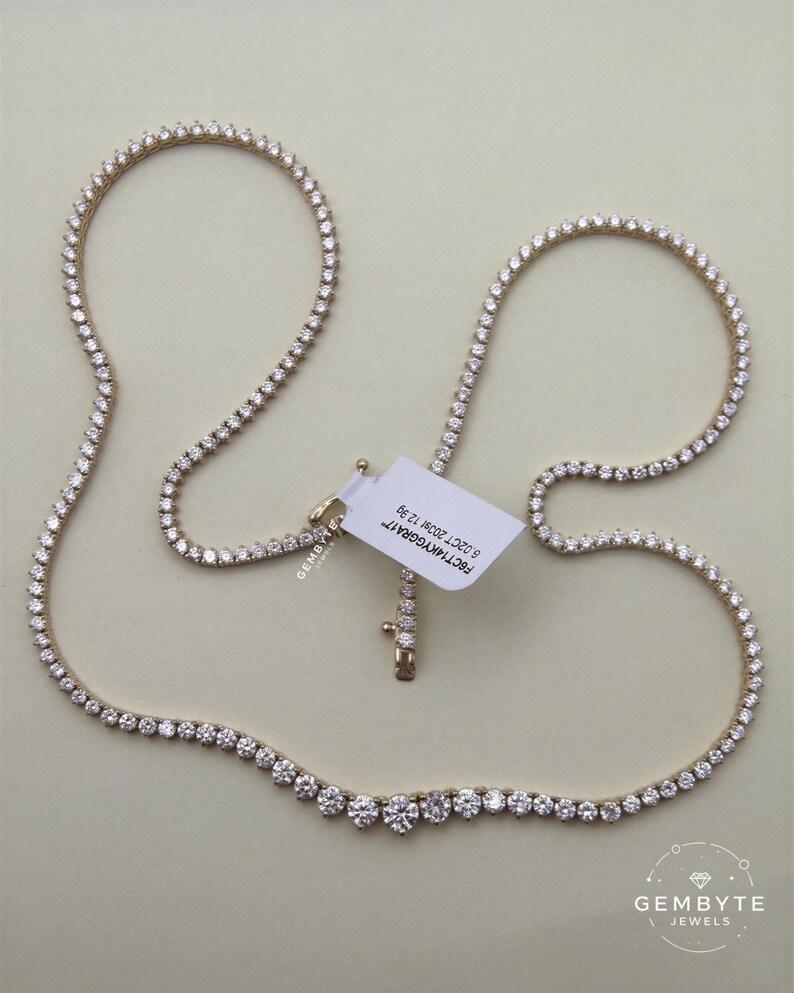 a gold necklace with numerous small diamonds arranged in a row, and a white tag attached to it.