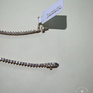 a necklace with a white tag attached to it, resting on a plain background.