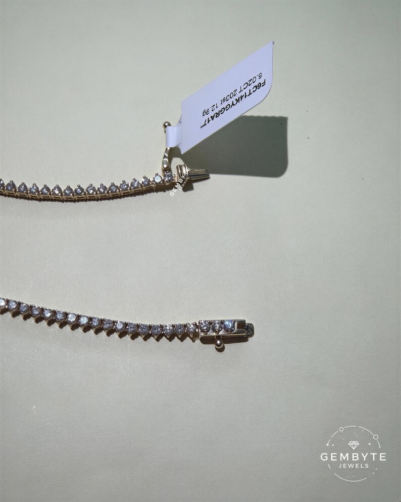 a necklace with a white tag attached to it, resting on a plain background.