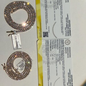 May include: Two 14k yellow gold necklaces with round brilliant laboratory grown diamonds, accompanied by two International Gemological Institute grading summary cards. The cards detail specifications including 10.00 and 8.05 total carat weights.