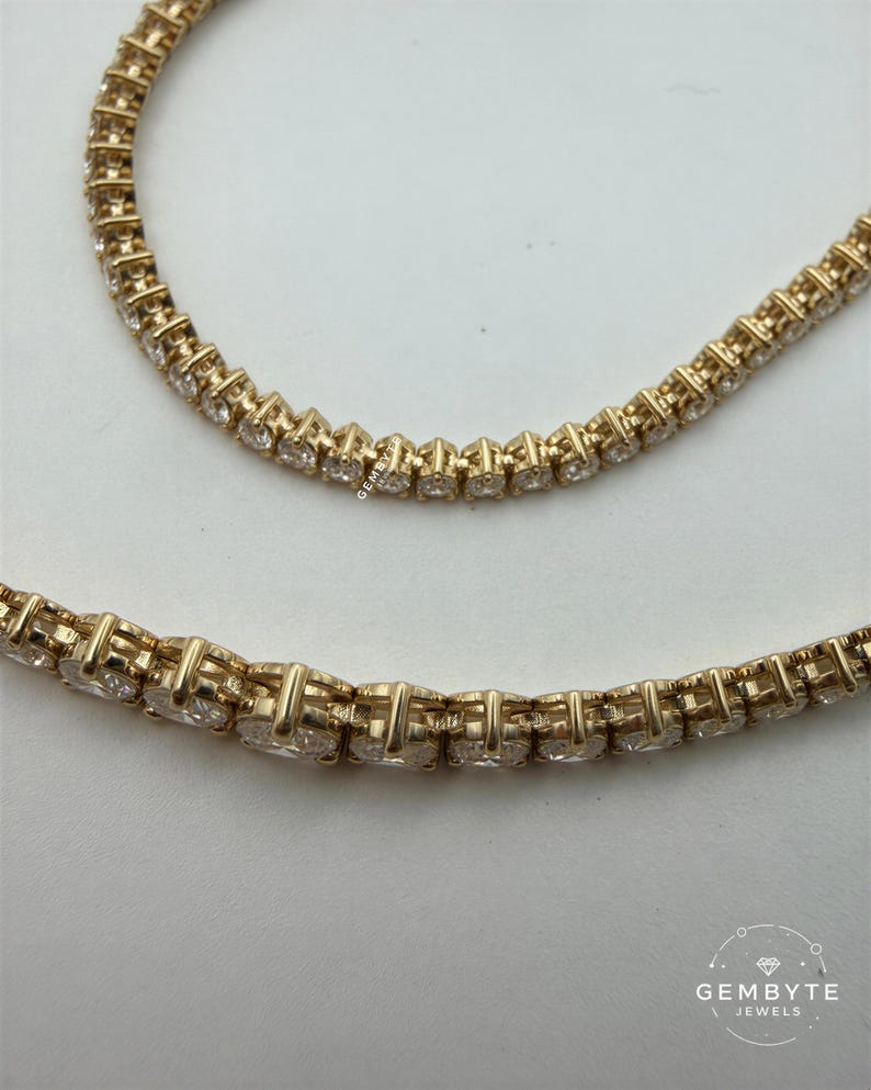 A close-up view of a gold necklace with numerous small diamonds set in the center.