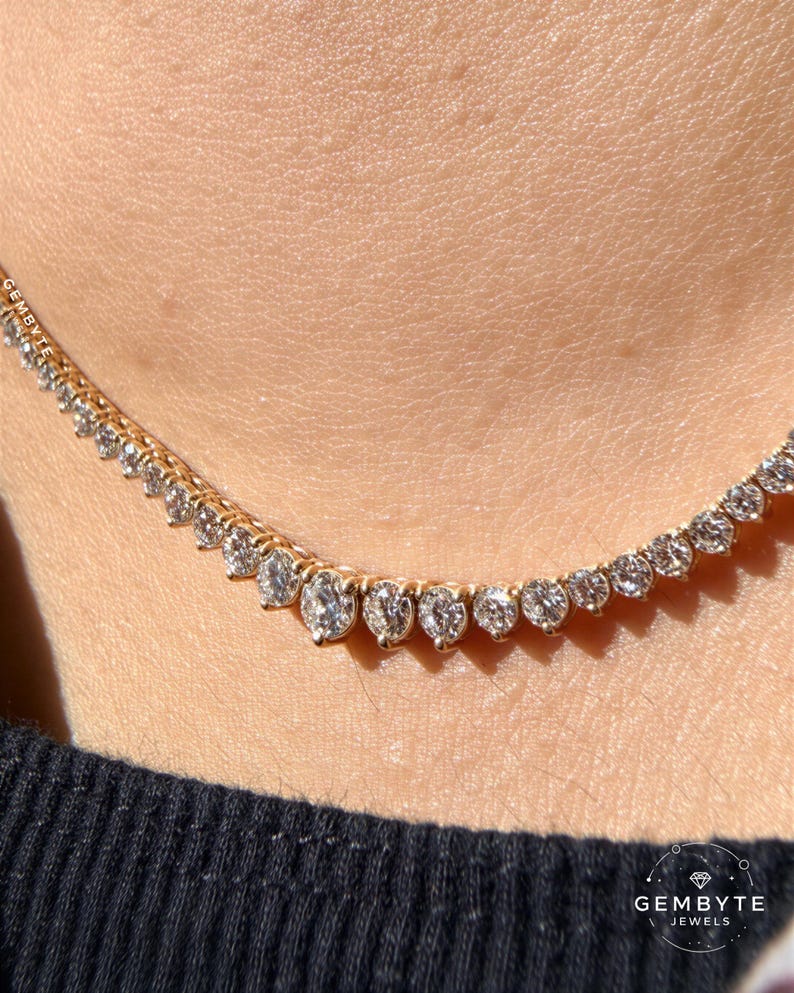 A close-up view of a delicate gold necklace with numerous small diamonds set in a row, worn around the neck of a person.
