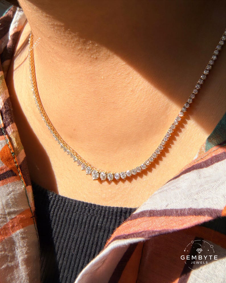 A close-up view of a person's neck and chest area wearing a gold necklace with a row of small diamonds.