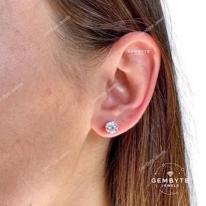 A close-up of a person's ear with a diamond earring in the earlobe.