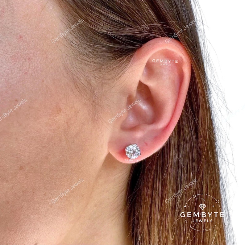 A close-up of a person's ear with a diamond earring in the earlobe.