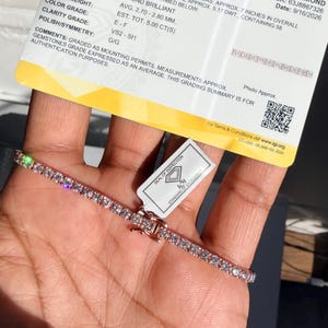 May include: A 14 karat pink gold tennis bracelet featuring round brilliant laboratory grown diamonds, accompanied by an International Gemological Institute grading summary card stating a length of 7 inches and a total weight of 5.00 carats.