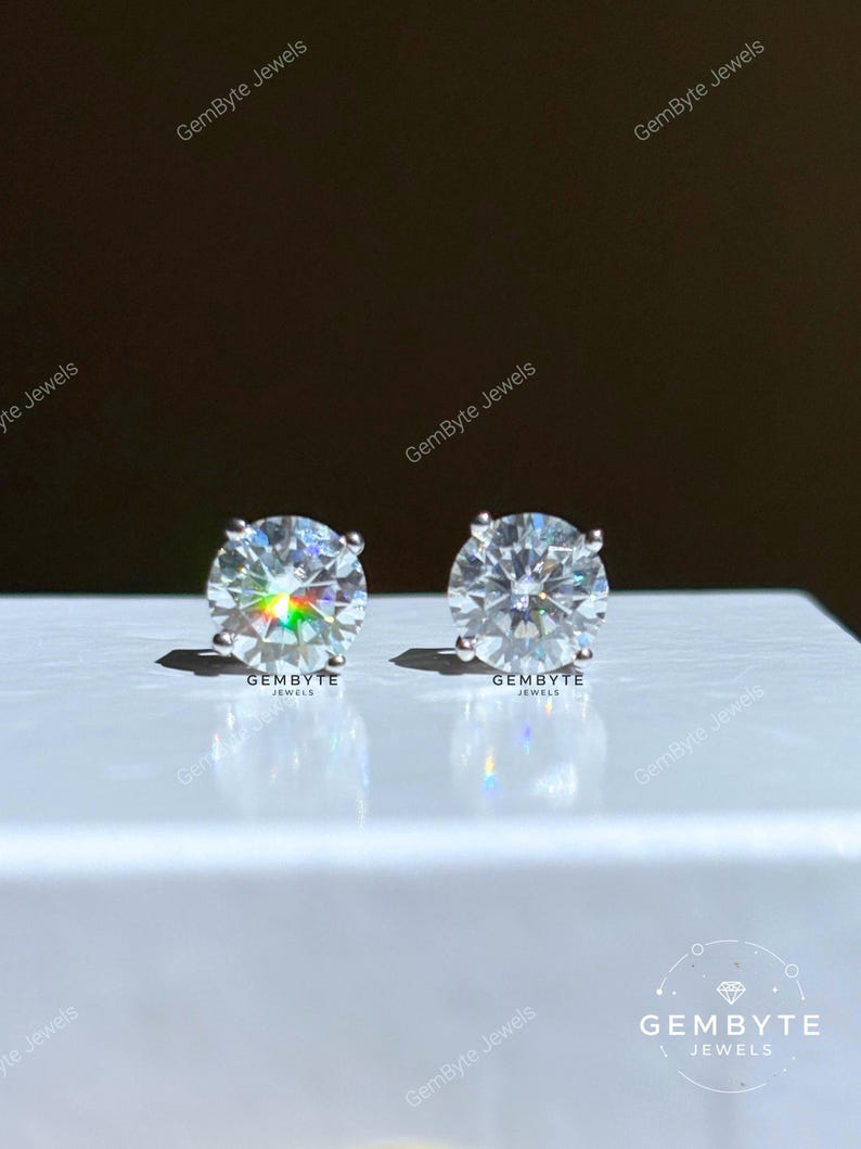 two large, clear, and sparkling diamond earrings placed on a white surface.