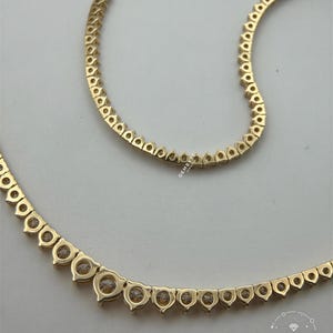 a gold necklace with a row of small diamonds or gemstones set in the center.