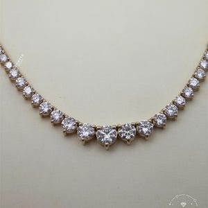 A necklace with a row of large, clear diamonds set in a gold-colored metal.