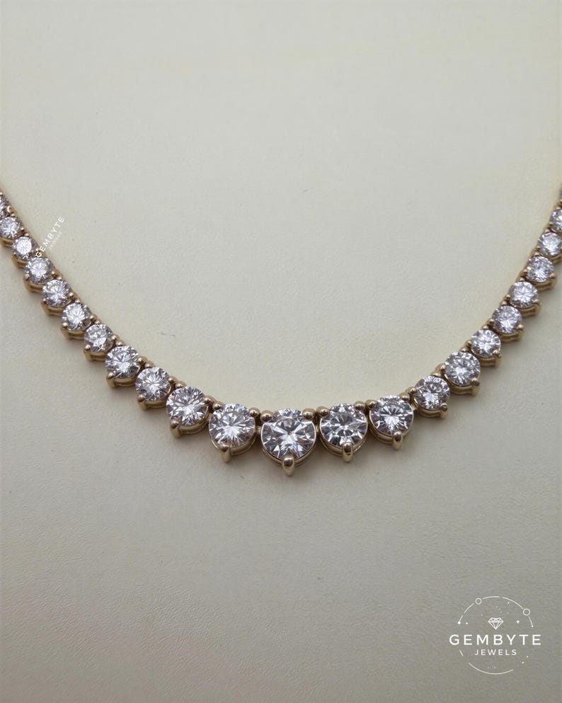 A necklace with a row of large, clear diamonds set in a gold-colored metal.