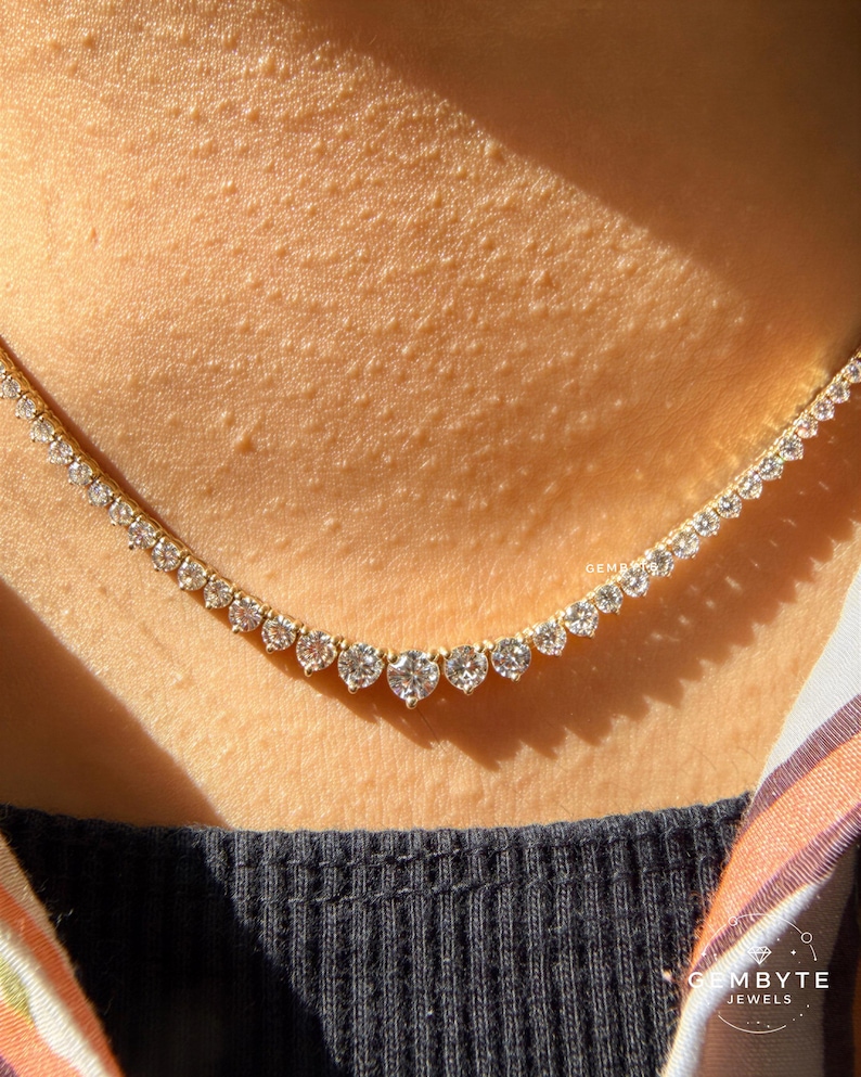 A close-up view of a delicate necklace with numerous small diamonds set in a gold chain, worn around the neck of a person.