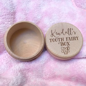 May include: A wooden tooth fairy box with a pink lid. The lid has the text "Kendall's Tooth Fairy Box" and a small illustration of a tooth with fairy wings.