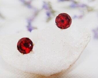 Peut inclure: Une paire de boucles d'oreilles en pierres précieuses rouges avec des montures en or. Les boucles d'oreilles sont sur un fond blanc.