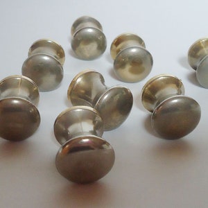 May include: Eight antique-style cabinet knobs with a gold finish. The knobs have a round top and a cylindrical base.