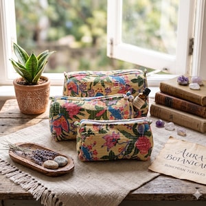 May include: Three rectangular zipped pouches made of yellow fabric with a multi-coloured floral pattern. The pouches feature a quilted texture and are arranged in a cluster. Each pouch has a zip closure and a soft, structured shape.