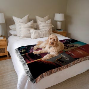 Puede incluir: Una manta tejida con un dise&ntilde;o de patchwork con texto e ilustraciones en tonos negros, rojos y turquesas. La manta tiene un borde con flecos y est&aacute; sobre una cama. Un perro est&aacute; acostado sobre la manta.