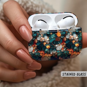 May include: Open AirPods Pro case with a stained glass effect design in teal, gold, and white. The case is held in a hand with long, polished nails. The text "STAINED GLASS EFFECT" is visible.