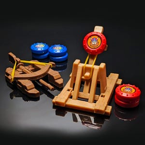 Puede incluir: Un juego de juguetes de catapulta y ballesta marrón con objetivos azules y rojos. La catapulta tiene una banda elástica amarilla. Los objetivos presentan un diseño vikingo. Un juguete divertido para niños.