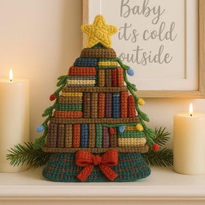 Può includere: Un albero di Natale all'uncinetto a forma di libreria, ornato da una stella gialla, luci a catena e un fiocco rosso. L'albero è su un caminetto con candele accese e un cartello incorniciato con la scritta "Baby it's cold outside".