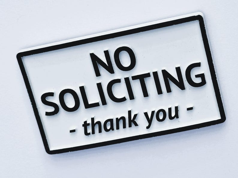 May include: White rectangular sign with black border and text "NO SOLICITING - thank you" in bold black letters. The sign is designed to discourage unwanted sales pitches.