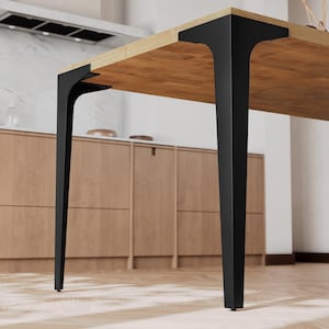 May include: A modern wooden table with a light brown tabletop and black metal legs. The legs are angular and provide a sturdy base. The table is designed for dining or working.
