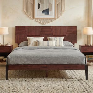 May include: A dark wood bed frame with a tall headboard featuring horizontal slats and geometric panels. The bed is dressed in a solid gray duvet and three decorative pillows with cream and blue striped patterns, flanked by two matching nightstands.