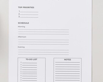 May include: A white Daily Planner sheet with black text. The top section is labeled "TOP PRIORITIES" with numbered lines. Below is a "SCHEDULE" section for morning, afternoon, and evening. The bottom has a "TO-DO LIST" and "NOTES" section.