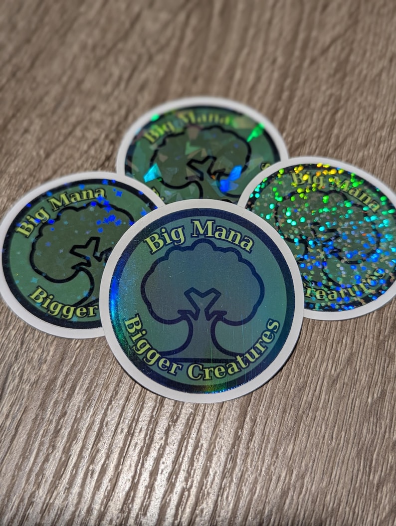 May include: Four round stickers with a holographic effect. Each sticker features a tree graphic within a blue circle, with the words "Big Mana" and "Bigger Creatures" in a white font. The stickers have a shiny, iridescent finish.