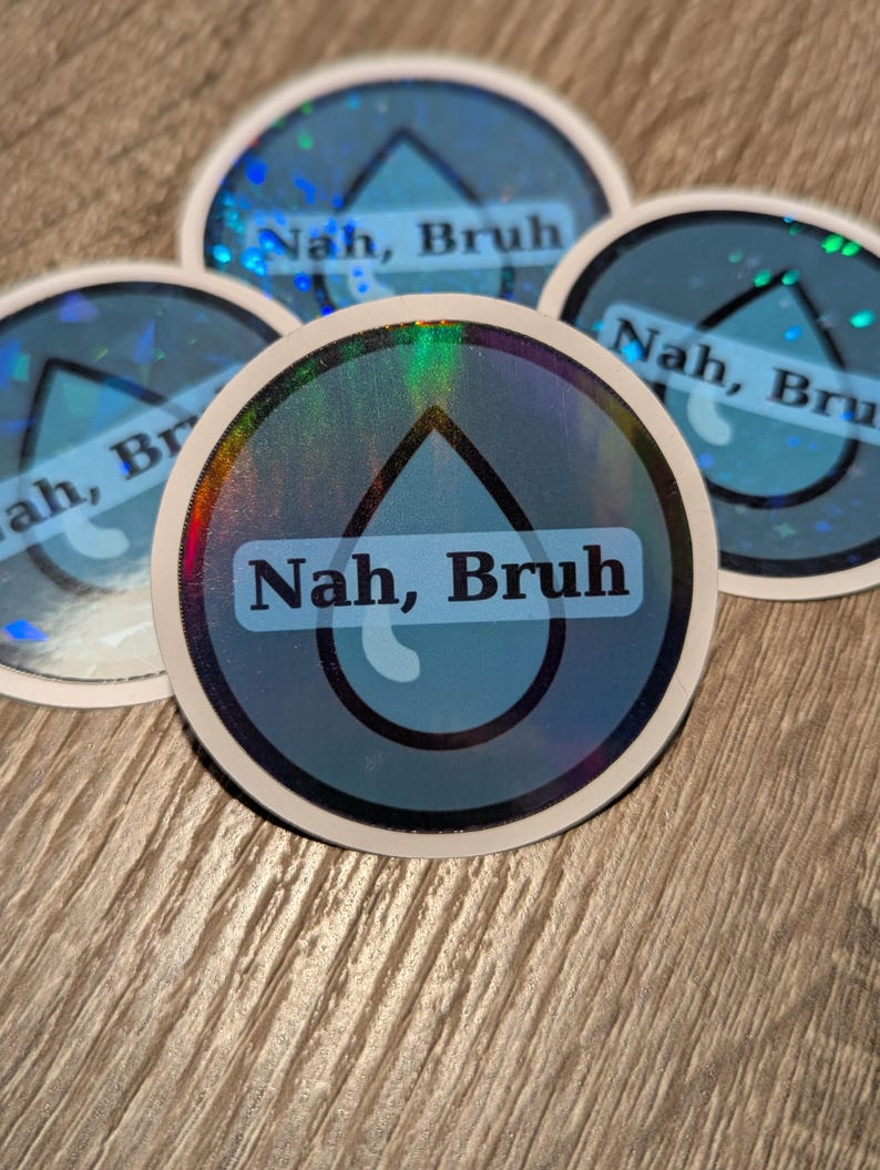 May include: A collection of round stickers with a holographic border and a blue water droplet design. The text "Nah, Bruh" is printed in a white, sans-serif font on a blue background. The stickers are arranged on a wooden surface.