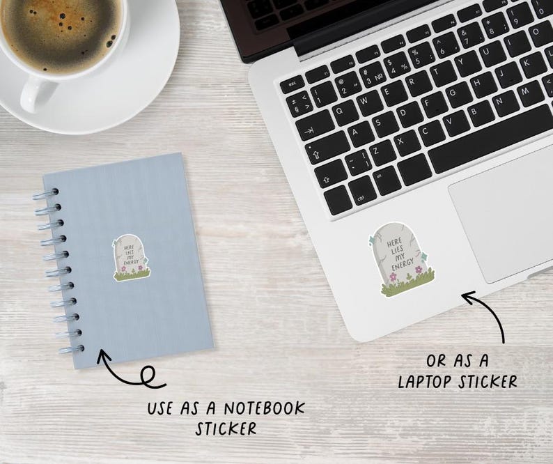 May include: A sticker with a tombstone design that reads "Here Lies My Energy." The sticker is shown on a notebook and a laptop, with arrows indicating its use as a notebook or laptop sticker. The tombstone is gray with green grass and pink and blue flowers.