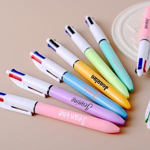May include: A selection of multi-coloured ballpoint pens. Each pen features a different pastel barrel colour, including pink, purple, yellow, green, and blue. The name "Jeanne" is printed on each pen in white script.