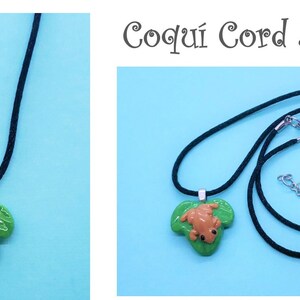 May include: A black cord necklace with a green leaf charm featuring a brown frog. The necklace is called "Coqu&iacute; Cord Necklace".
