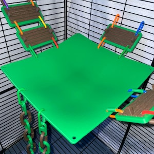 May include: A bright green square platform for a small animal cage, featuring three brown textured rectangular platforms attached by colorful plastic links and two brown plastic chains hanging from the bottom corners of the main green platform.