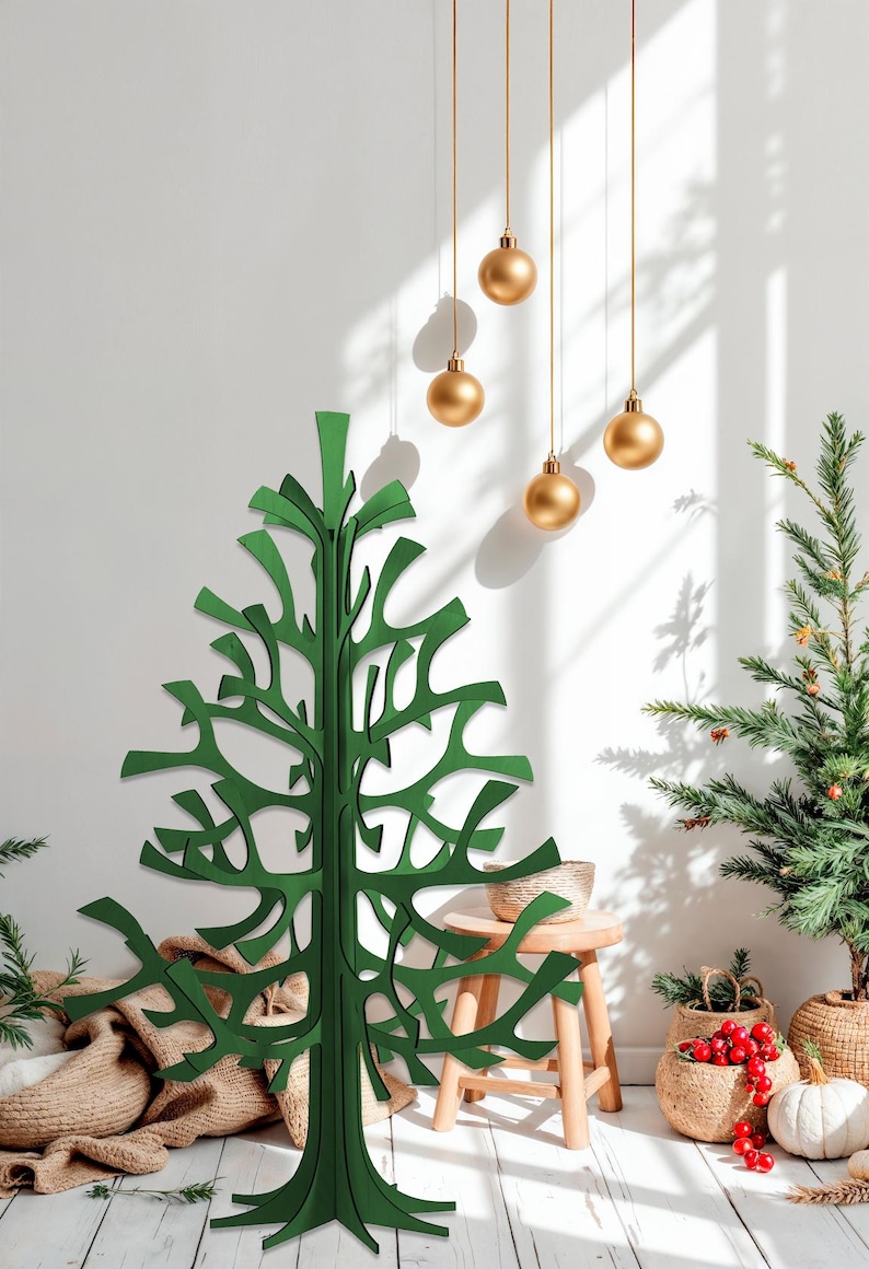 K&ouml;nnte beinhalten: Ein gr&uuml;ner, moderner Weihnachtsbaum aus ausgeschnittenem Holz steht vor einer wei&szlig;en Wand. Goldene Kugeln h&auml;ngen von der Decke. Ein kleiner Weihnachtsbaum und andere Weihnachtsdekorationen befinden sich im Hintergrund. Der Baum ist ein einzigartiges, modernes Design.