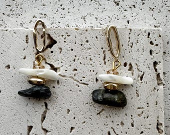 May include: A pair of dangle earrings featuring an irregular gold-tone metal hoop at the top, followed by a small clear bead, a horizontal white stone piece, a small gold-tone spacer, and a dark gray stone at the bottom.
