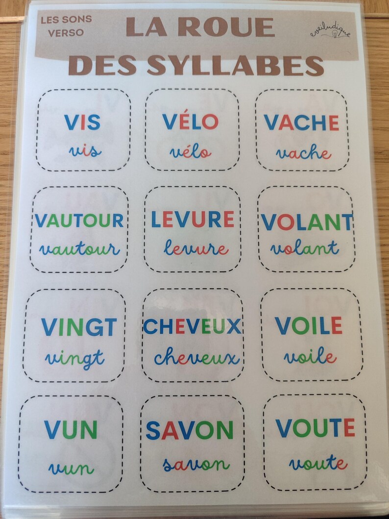 May include: A colorful educational game for learning French syllables. The game features 12 squares with different French words, each with a different color scheme. The words are: "vis", "v&eacute;lo", "vache", "vautour", "levure", "volant", "vingt", "cheveux", "voile", "vun", "savon", and "voute".