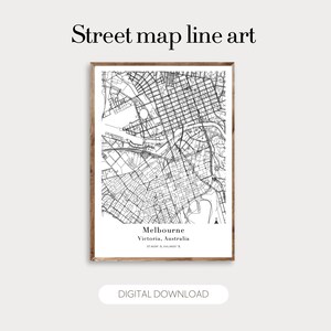 May include: A framed black and white street map line art print of Melbourne, Victoria, Australia. The print includes the city's name, coordinates, and the text "DIGITAL DOWNLOAD". The artwork is encased in a brown wooden frame.