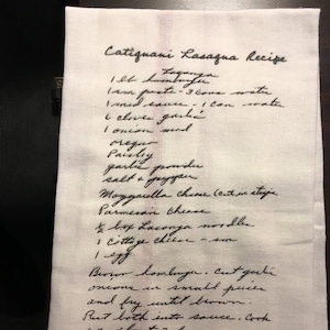 May include: Handwritten recipe for Catignani Lasagna, listing ingredients such as 1 lb hamburger, 1 can tomato paste, 3 cans water, 1 med onion, 6 cloves garlic, 1 onion med, oregano, parsley, garlic powder, salt and pepper, mozzarella cheese, parmesan cheese, 1 box lasagna noodles, 1 cottage cheese, 1 jar of sauce. The recipe instructs to brown the hamburger and onions in small pieces and then add them to the sauce.