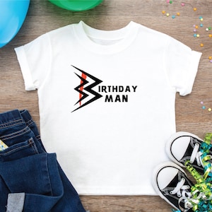 May include: White t-shirt with a black lightning bolt graphic and the text "Birthday Man".