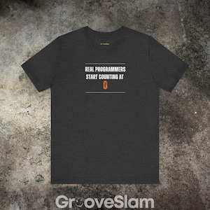 Op de afbeelding: Donkergrijs t-shirt met een witte afbeelding met de tekst "REAL PROGRAMMERS START COUNTING AT 0".
