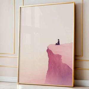 May include: Framed art print featuring a person in silhouette meditating on a cliff edge. The artwork has a gradient of pink and purple hues, with a gold frame. The background is a soft, pale color.
